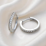 Sterling silver pavé cubic zirconia huggie hoops from Silversmiths displayed on a soft, light background.