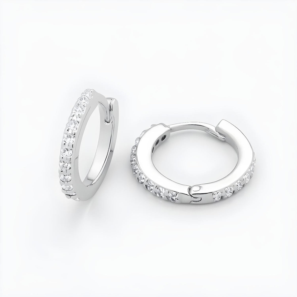 Sterling silver huggie hoop earrings with cubic zirconia are displayed against a plain white background.