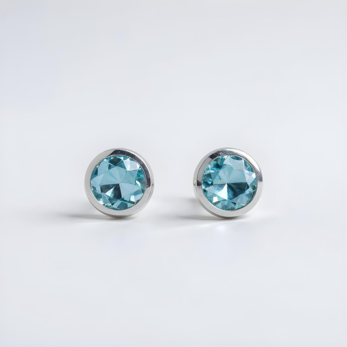 Sterling silver stud earrings with round simulated London topaz gemstones in bezel settings.