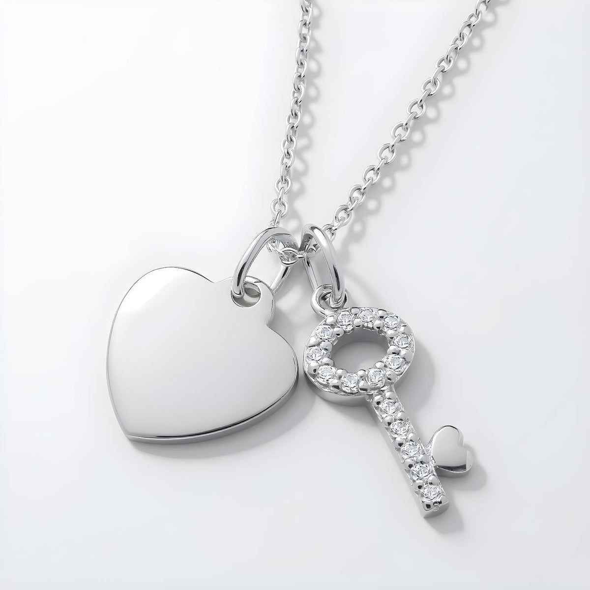 Sterling silver necklace with cubic zirconia heart and key pendants that have a sparkling finish.