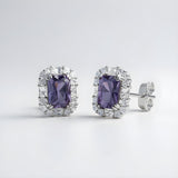 Emerald-cut simulated tanzanite halo stud earrings in sterling silver by Silversmiths on a plain background.