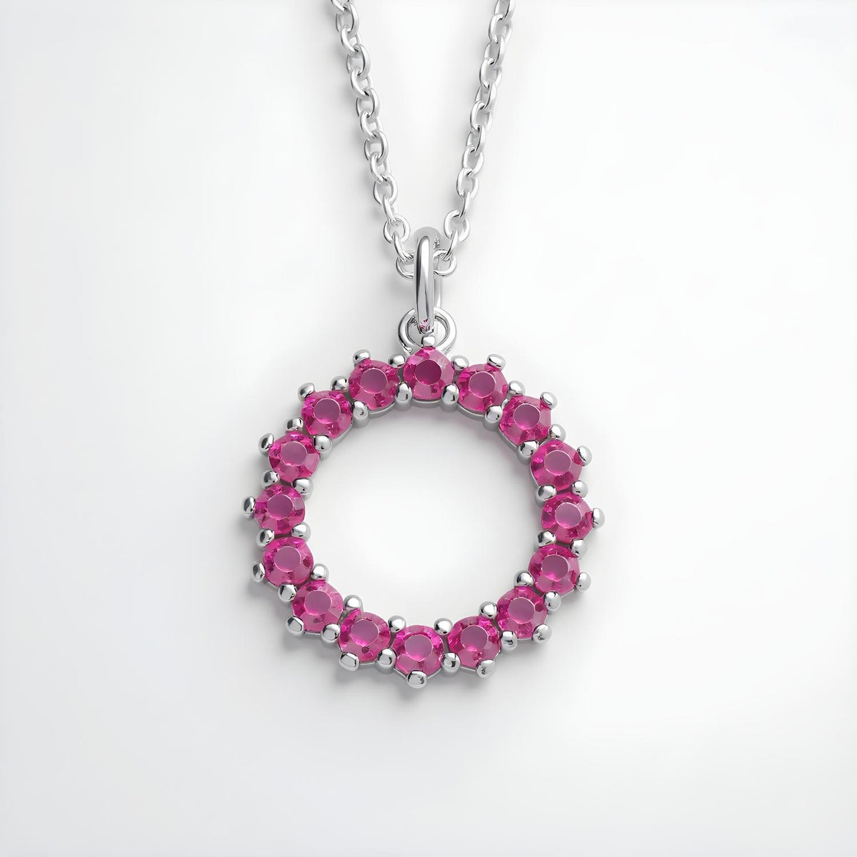 Sterling silver circle necklace with simulated ruby and sparkling pink stones, shown on a plain white background.