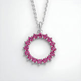 Sterling silver circle necklace with simulated ruby and sparkling pink stones, shown on a plain white background.
