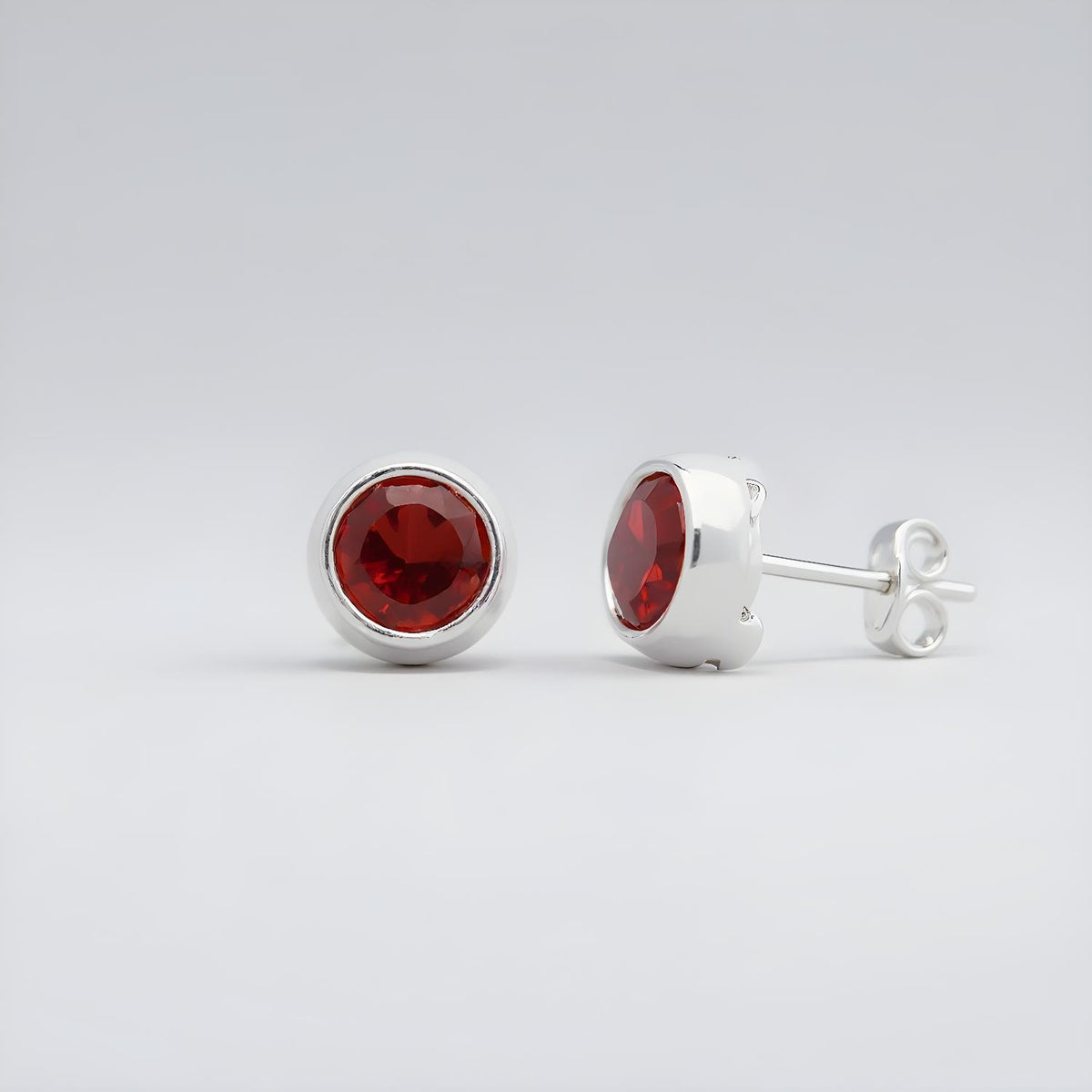 Silversmiths sterling silver stud earrings with natural garnet stones on a light gray background.