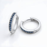 Silversmiths sterling silver huggie hoop earrings with simulated sapphires on a plain white background.
