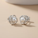 Silversmiths sterling silver open knot stud earrings with freshwater pearls on a beige surface.