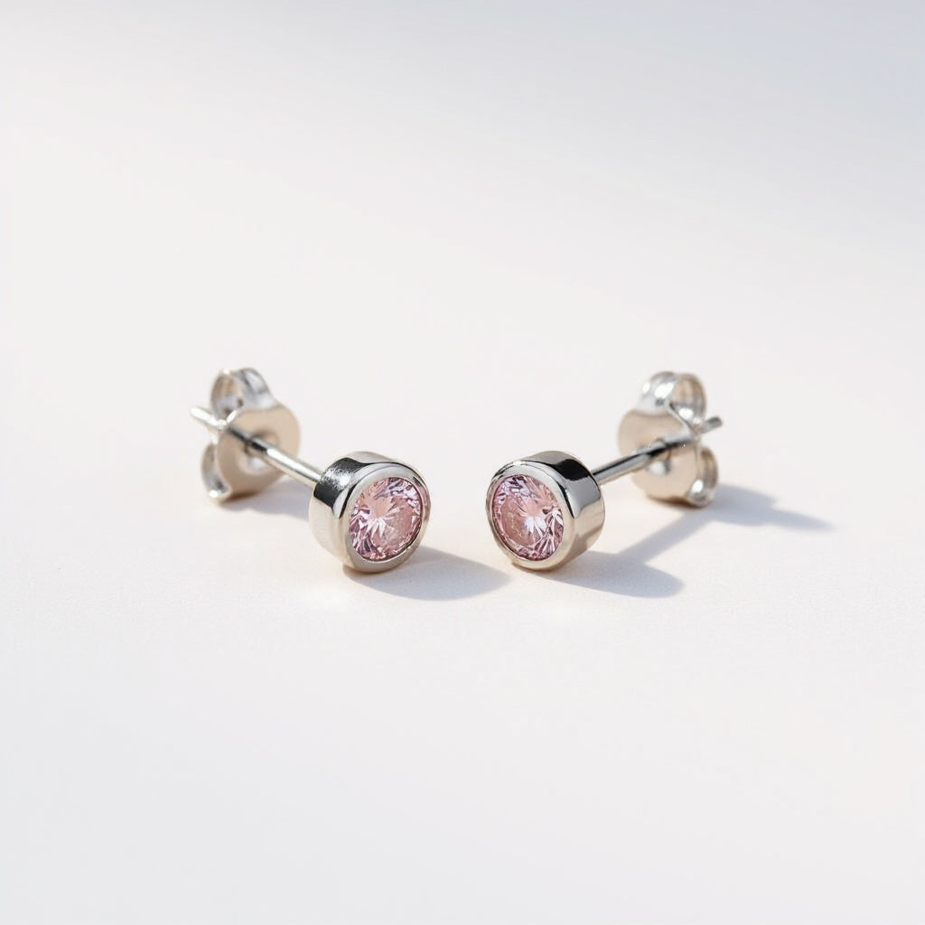 Silversmiths sterling silver stud earrings feature faceted pink simulated sapphire stones in bezel settings.
