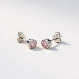 Silversmiths sterling silver stud earrings feature faceted pink simulated sapphire stones in bezel settings.