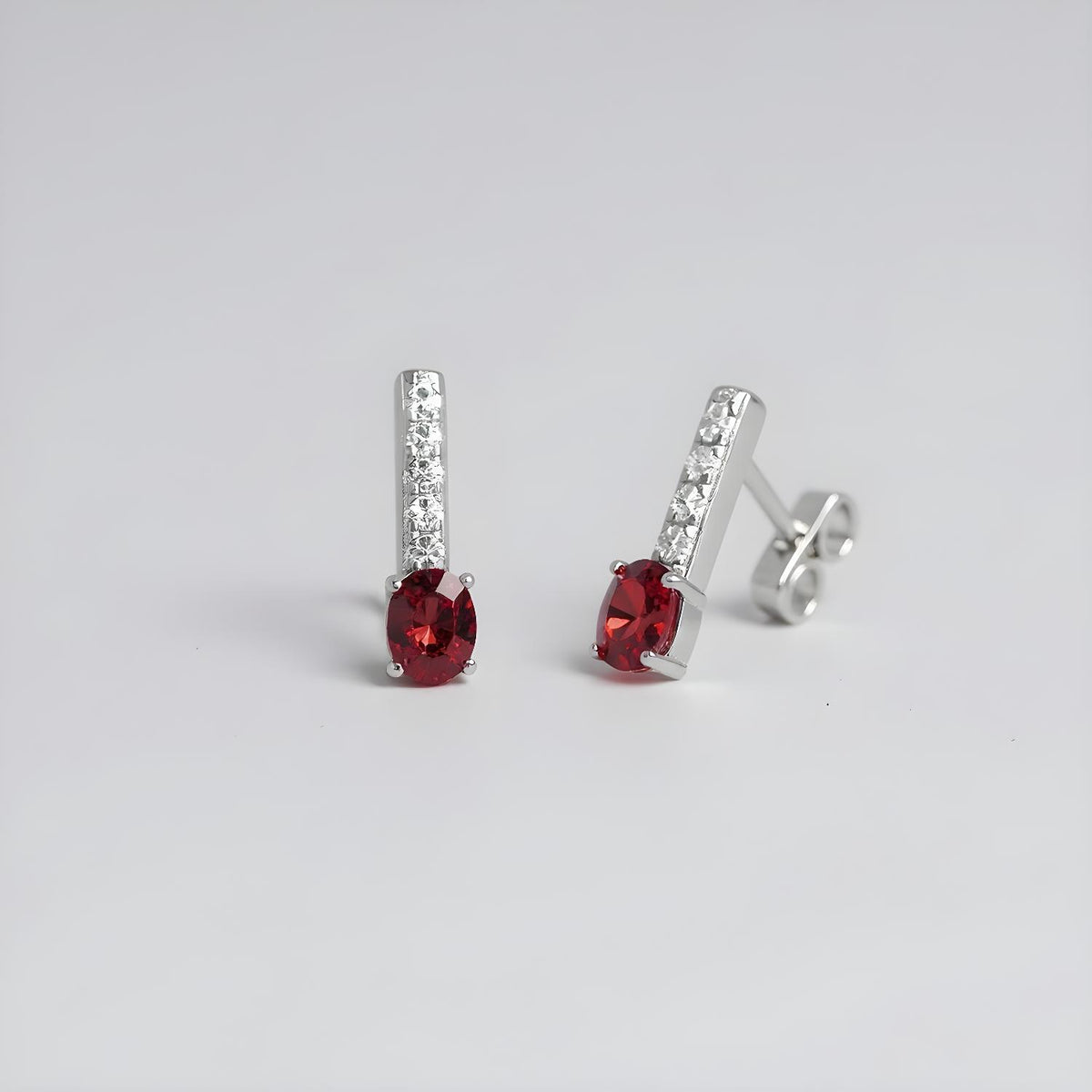 Sterling silver drop studs featuring simulated rubies and cubic zirconia accents.