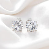 Silversmiths sterling silver stud earrings with 7mm round cubic zirconia, displayed on white fabric.