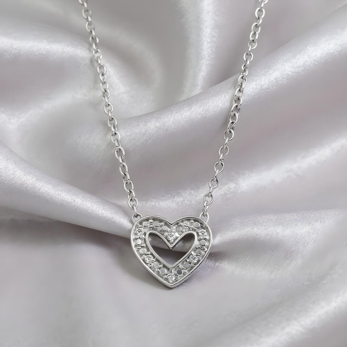 A sterling silver double heart diamond necklace by Silversmiths rests on satin fabric.