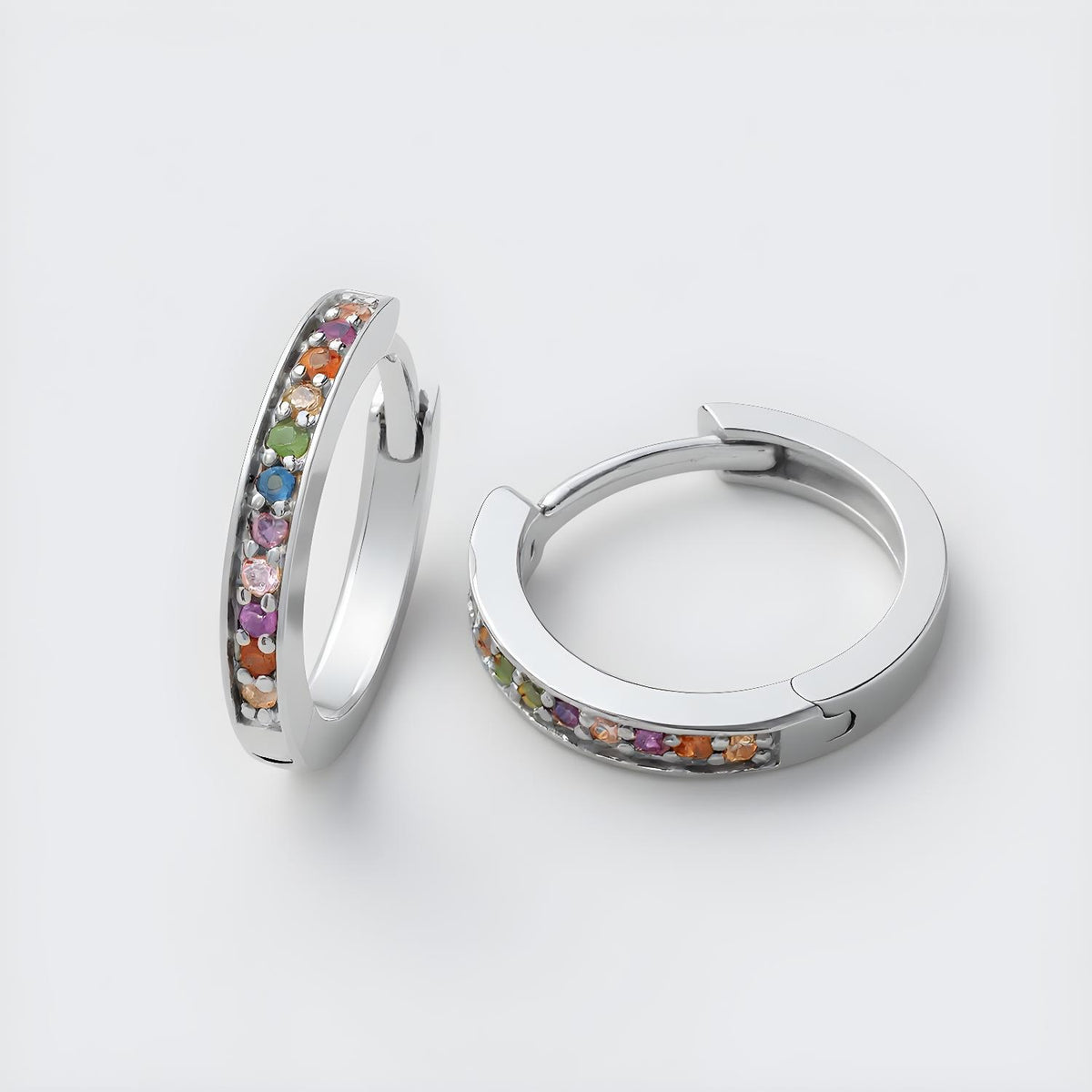 Sterling silver huggie hoops with multicolored cubic zirconia stones in a rainbow pattern.