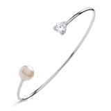 Silversmiths sterling silver torque bangle featuring a heart-cut cubic zirconia and a faux pearl accent.