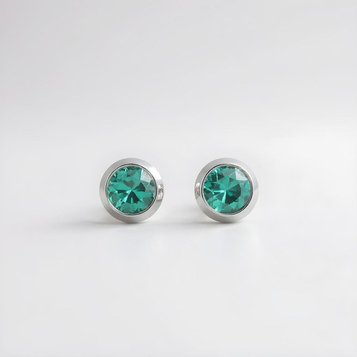 Silversmiths Sterling Silver stud earrings with 4mm simulated emeralds shown on a plain white background.