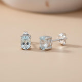 Sterling silver oval stud earrings feature natural blue topaz stones, crafted by Silversmiths.