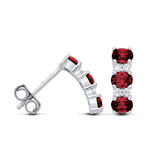 Sterling silver stud earrings featuring three simulated rubies in a drop design with clear accent stones.