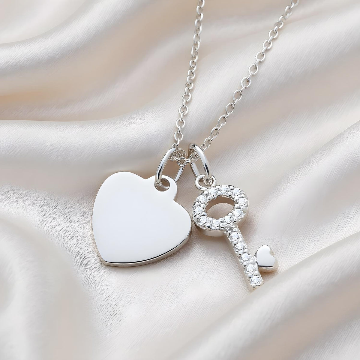 Silversmiths sterling silver necklace with cubic zirconia heart and key pendants on a soft satin background.