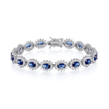 A sterling silver bracelet featuring oval simulated sapphires in a halo design is shown on a white background.