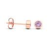 Rose gold plated silversmith studs with faceted Alexandrite in bezels, shown from side and front on white background.