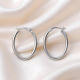 Silversmiths sterling silver oval hoop earrings, 24.75mm, displayed on smooth silky fabric.