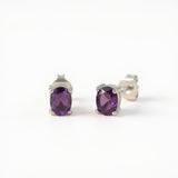 Sterling silver oval stud earrings with natural amethyst gemstones, displayed on a plain white background.
