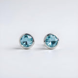 Sterling silver stud earrings with round simulated London topaz gemstones in bezel settings.