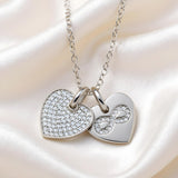 Sterling silver double heart necklace with an infinity charm, cubic zirconia accents, and engraved infinity symbol.
