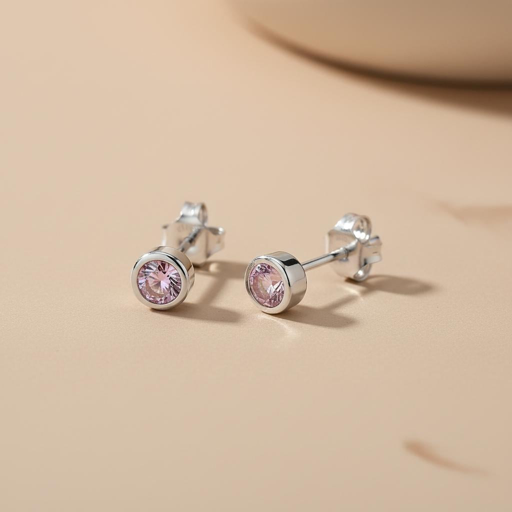 Silversmiths sterling silver stud earrings with faceted simulated alexandrite on a light beige surface.