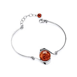 A Sterling Silver bracelet features a round Cognac Baltic amber cabochon and an adjustable chain against a white background.
