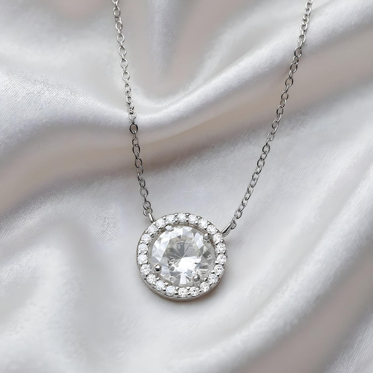 Sterling silver necklace by Silversmiths features a round pendant with cubic zirconia halo and shimmering gemstones.