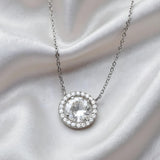 Sterling silver necklace by Silversmiths features a round pendant with cubic zirconia halo and shimmering gemstones.
