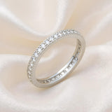 A sterling silver CZ eternity ring by Silversmiths rests on cream-colored satin fabric.