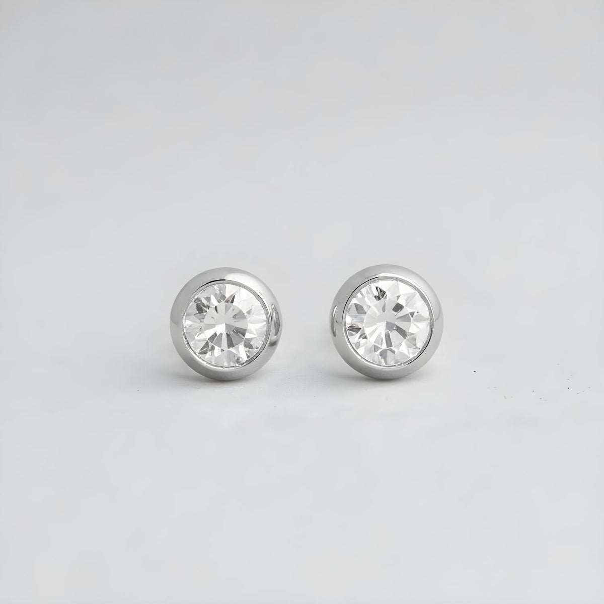 4mm sterling silver bezel-set cubic zirconia stud earrings with a minimalist design on a light gray background.