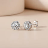 Silversmiths sterling silver round cubic zirconia halo stud earrings on beige, viewed from front and side.