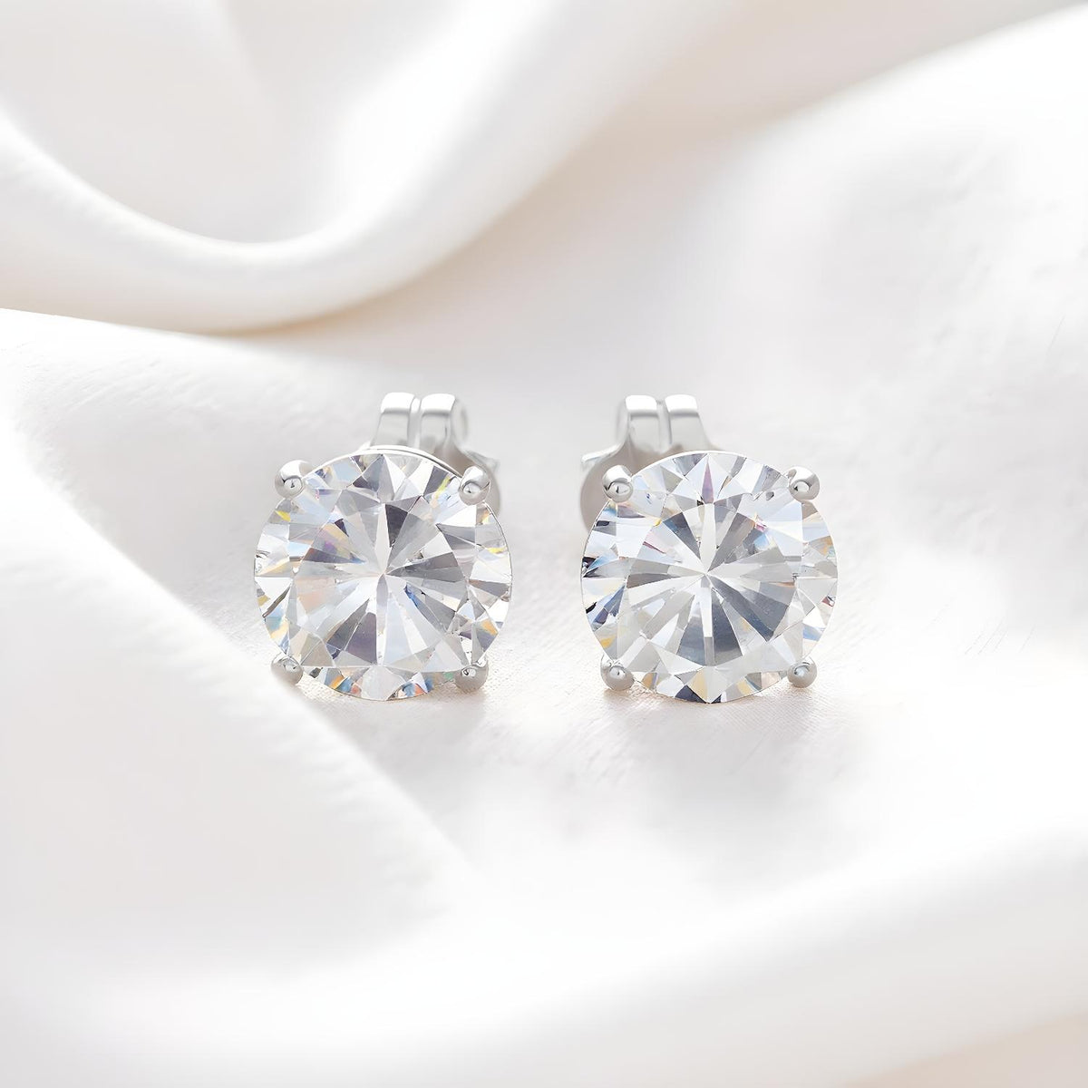 Silversmiths sterling silver stud earrings with 7mm round cubic zirconia, displayed on white fabric.