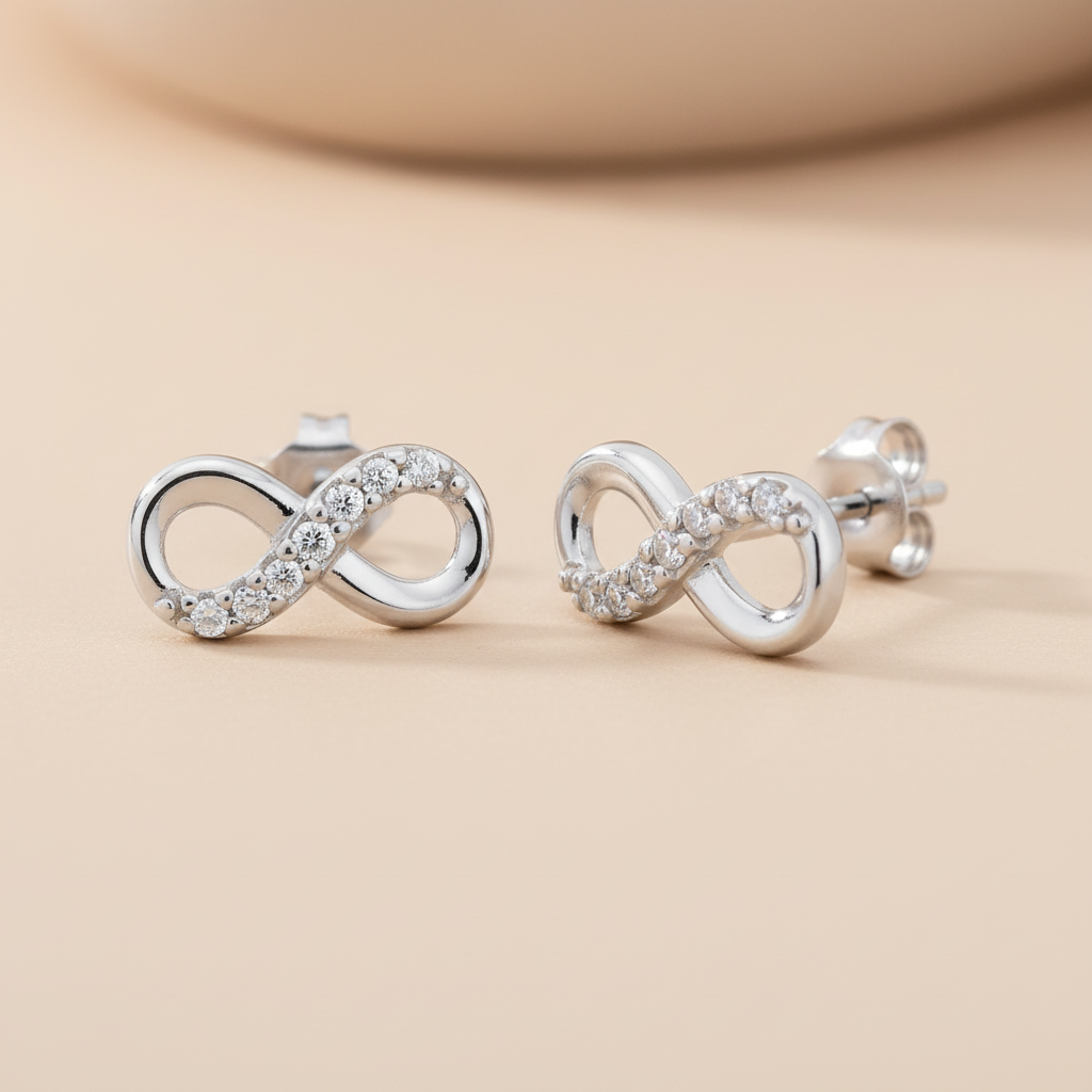 Silversmiths sterling silver infinity stud earrings with cubic zirconia rest on a light beige surface.