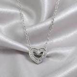 A sterling silver double heart diamond necklace by Silversmiths rests on satin fabric.