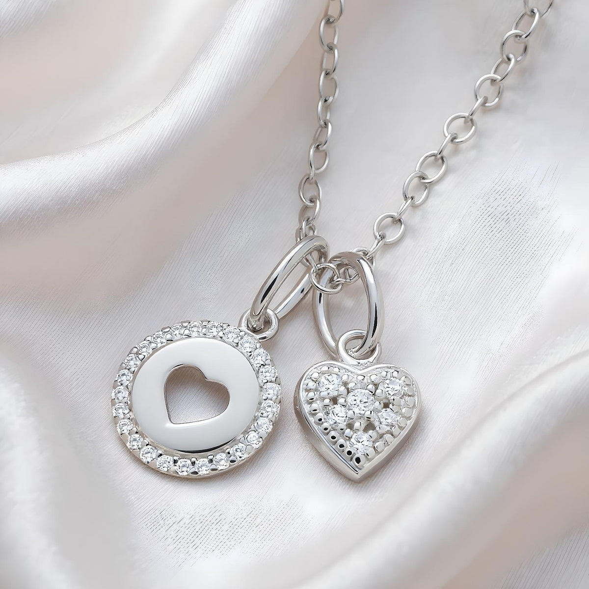 Silversmiths: Two silver necklaces, one with a heart cutout and one with a cubic zirconia heart and halo charm.