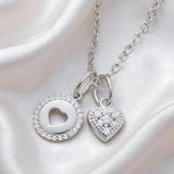 Silversmiths: Two silver necklaces, one with a heart cutout and one with a cubic zirconia heart and halo charm.