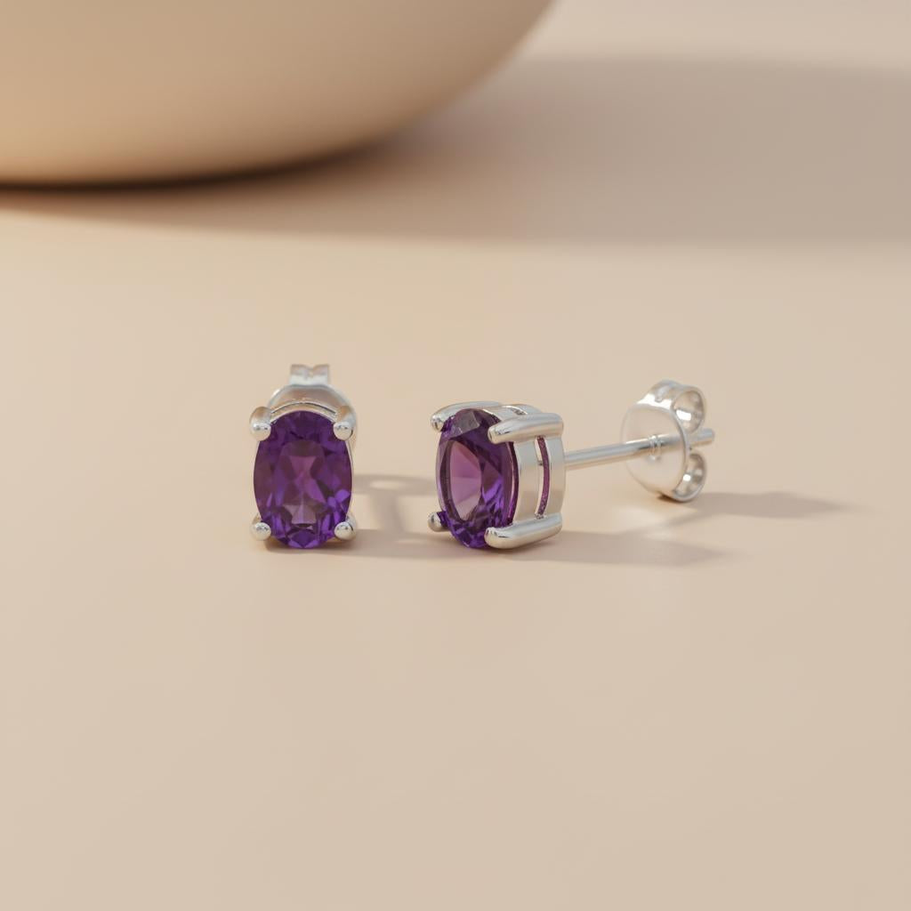 Silversmiths sterling silver oval stud earrings with natural amethyst on a smooth light-colored surface.