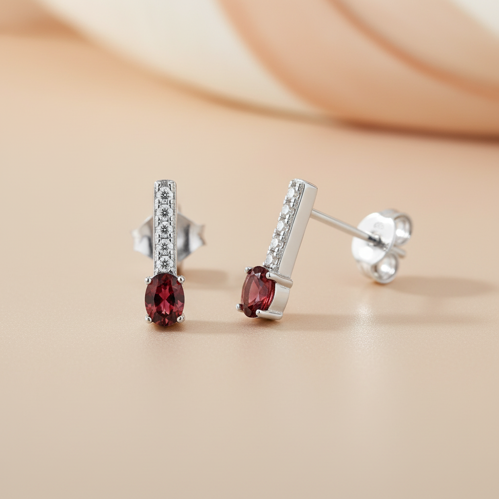 Sterling silver drop stud earrings with simulated ruby and CZ stones shown on a beige surface.