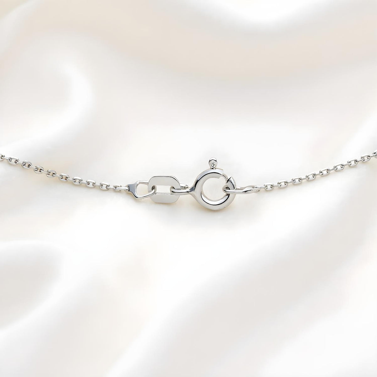 A sterling silver 1mm diamond cut rolo chain necklace with a spring ring clasp, displayed on white fabric.