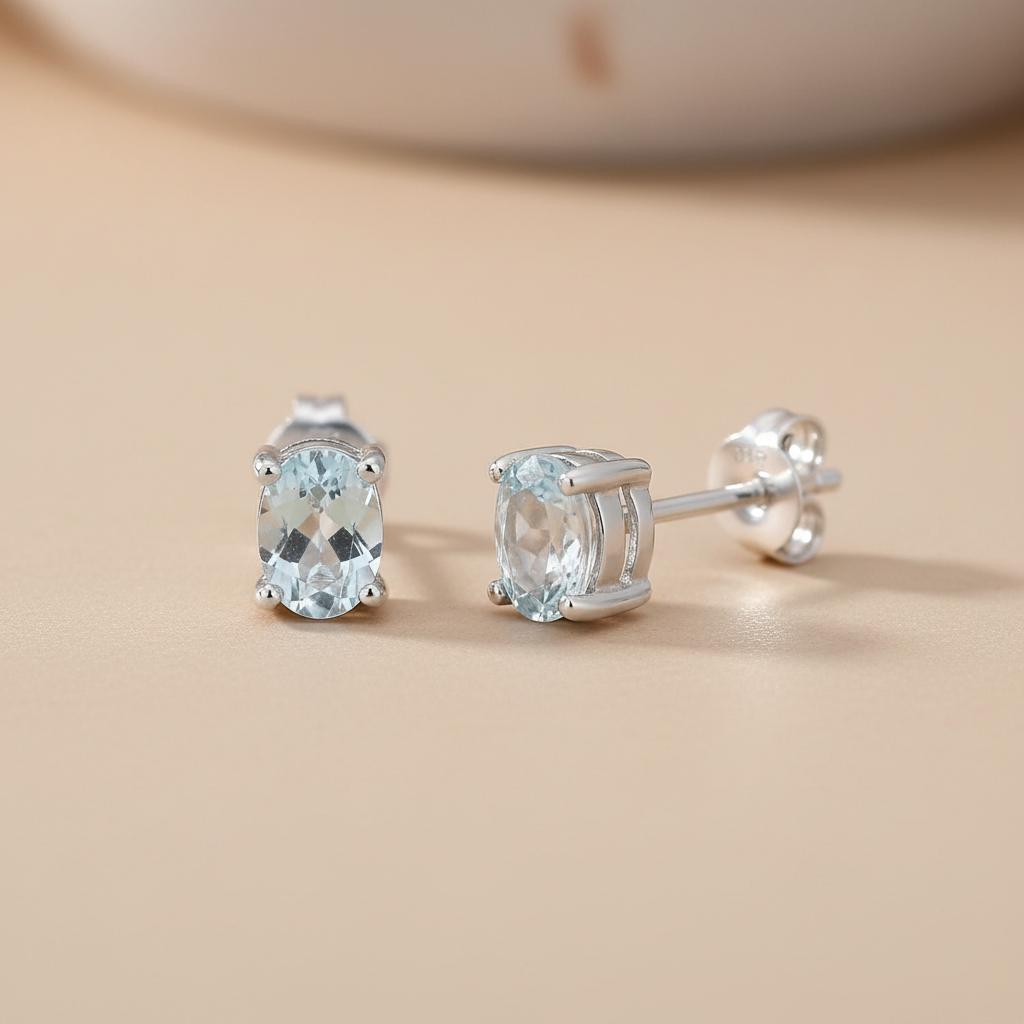 Sterling silver oval stud earrings feature natural blue topaz stones, crafted by Silversmiths.