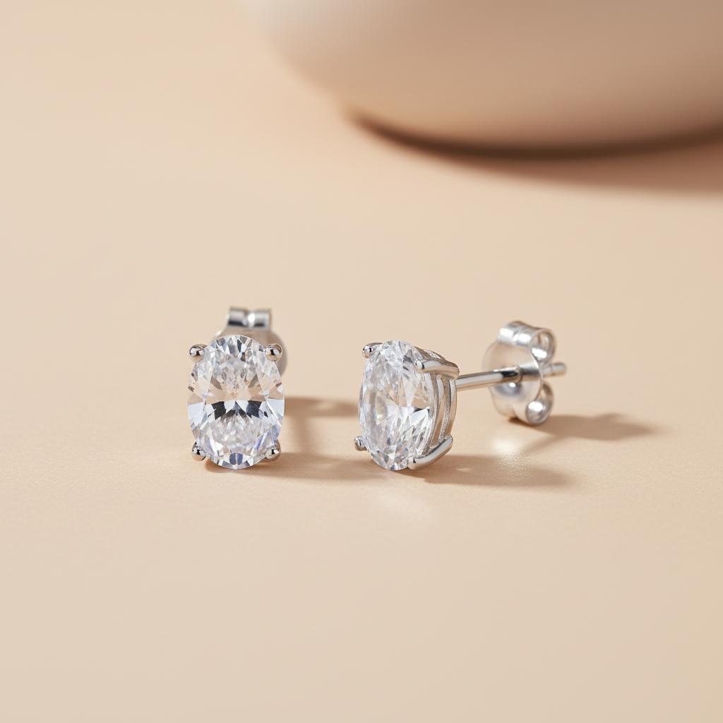 Silversmiths 7x5mm oval cubic zirconia stud earrings in sterling silver on a light beige background with soft shadow.