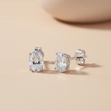 Silversmiths 7x5mm oval cubic zirconia stud earrings in sterling silver on a light beige background with soft shadow.