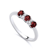 Sterling silver ring with three simulated rubies and four cubic zirconia in a trilogy design by Silversmiths.