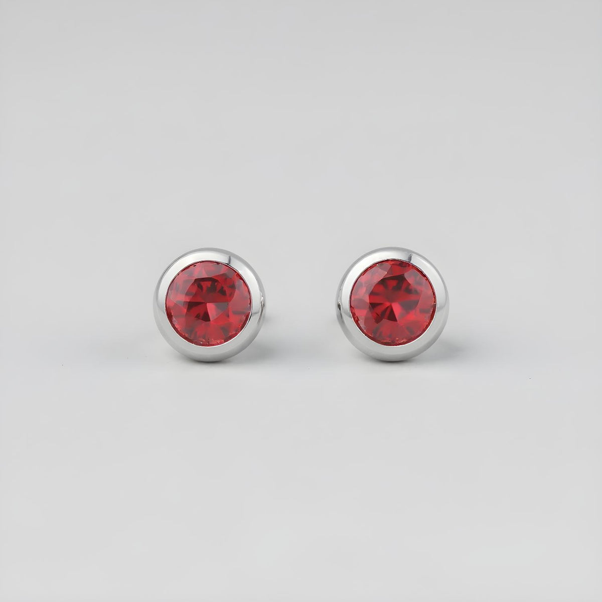 Silversmiths sterling silver stud earrings with simulated garnet stones, displayed on a sleek gray background.