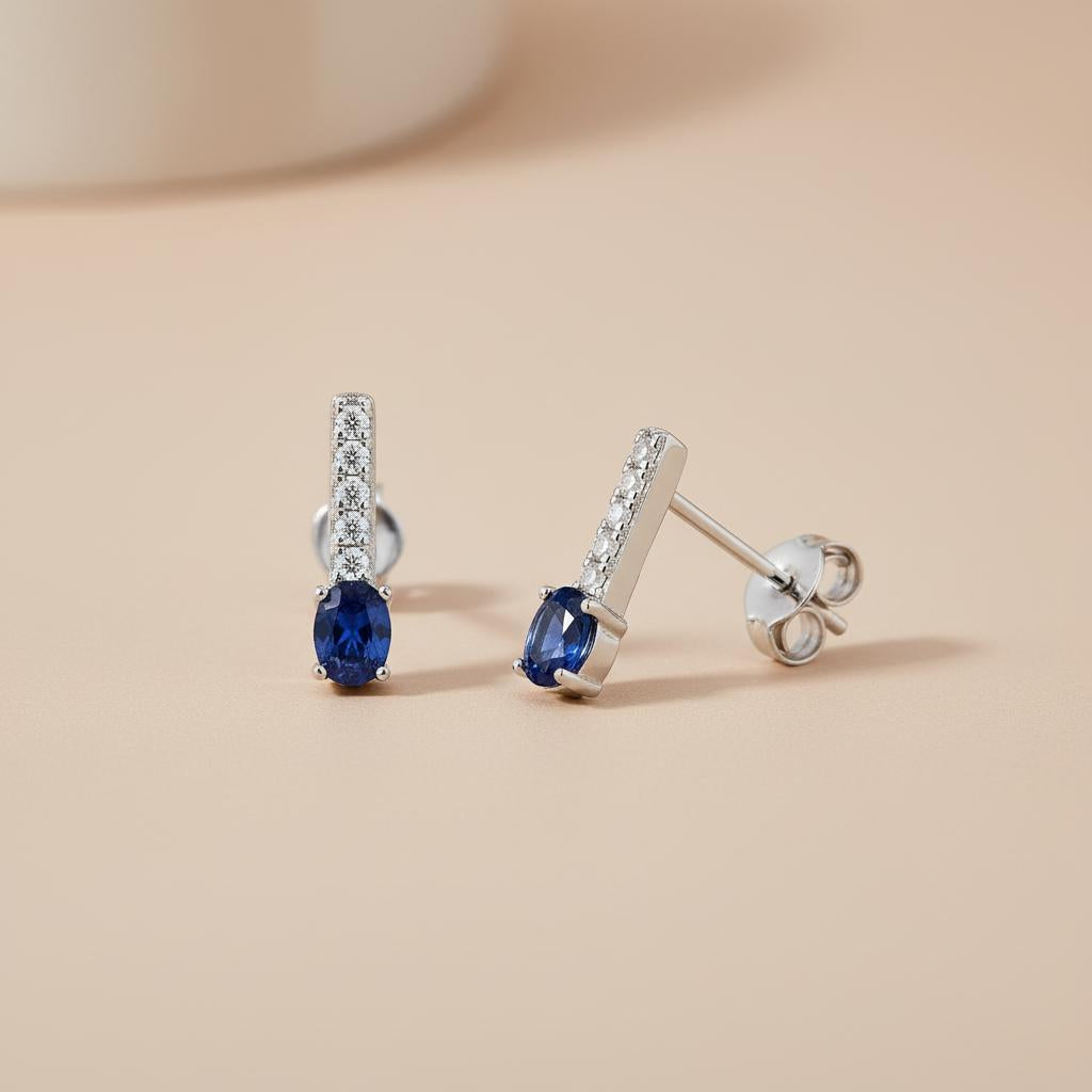 Silversmiths sterling silver drop studs with simulated sapphire and cubic zirconia displayed on a beige surface.