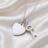 Silversmiths sterling silver necklace with cubic zirconia heart and key pendants on a soft satin background.