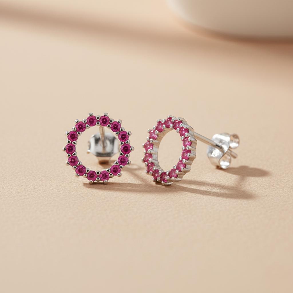 Silversmiths sterling silver stud earrings with simulated ruby circles rest on a beige surface.